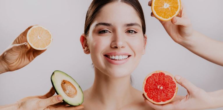 Lady with glowing skin surrounded by a variety of fruits