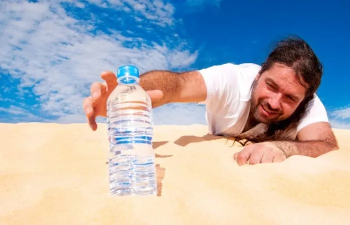 Man reaching for a bottle of water in the desert
